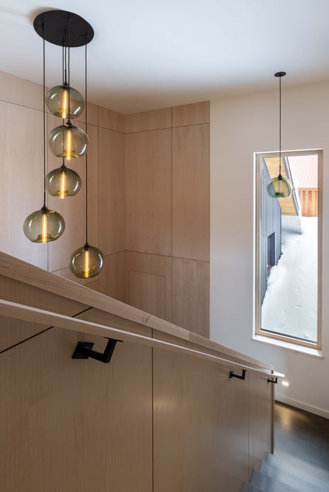 Niche's Circular-5 Canopy with 5 moss stamen glass lighting pendants, and one single glass lighting pendant hangs in the window