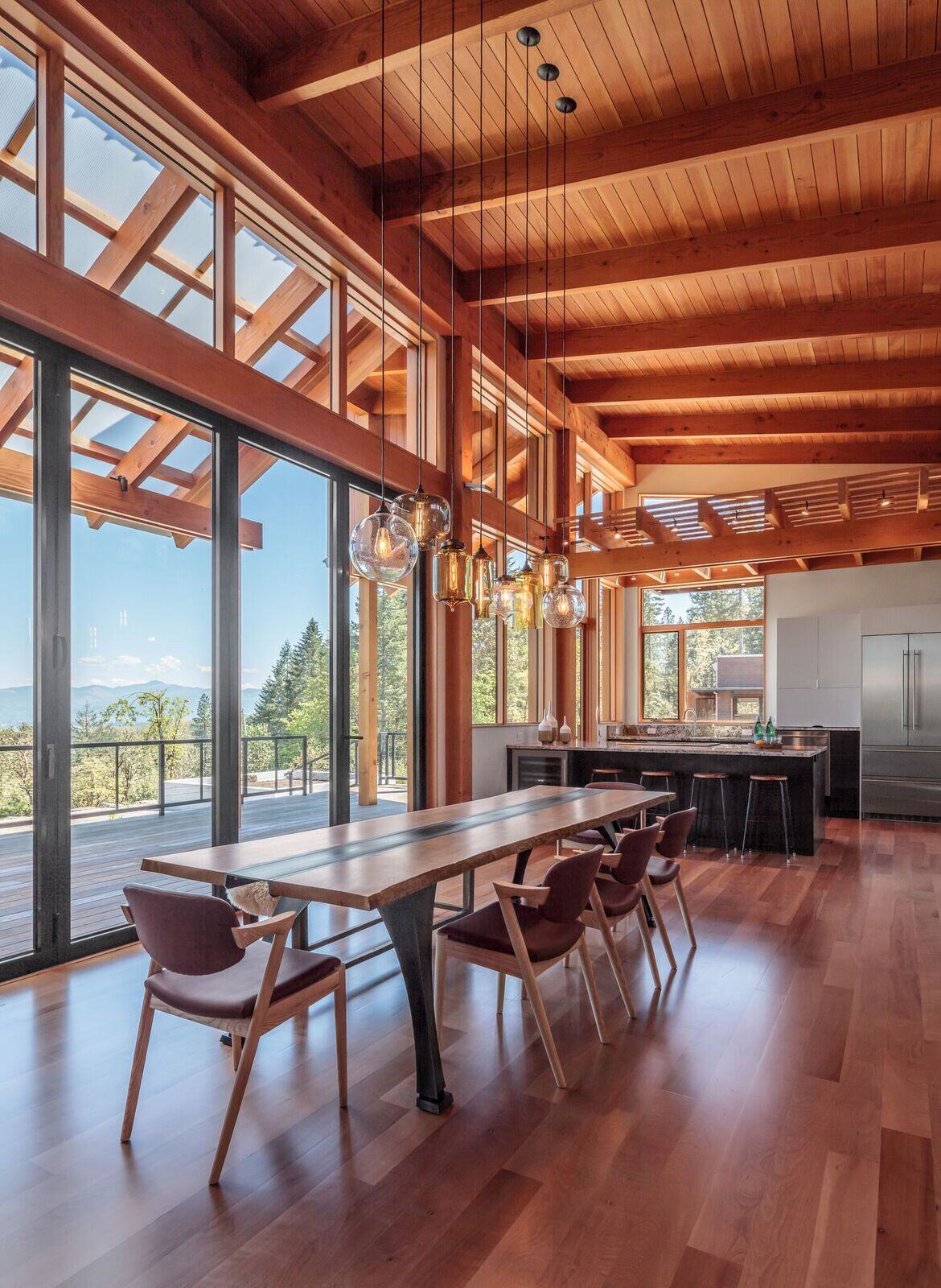 Timberidge home by 2form architecture with Niche handmade glass lighting pendants Effervescent Solitaire, Smoke Oculo, Amber Bella, Smoke Pharos, Amber Turret, Effervescent Minaret, and Grey Oculo hang above dining room table
