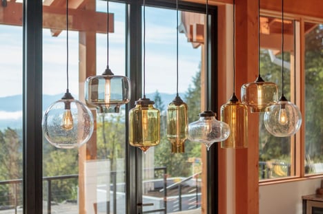 Timberidge home by 2form architecture with Niche handmade glass lighting pendants Effervescent Solitaire, Smoke Oculo, Amber Bella, Smoke Pharos, Amber Turret, Effervescent Minaret, and Grey Oculo hang above dining room table